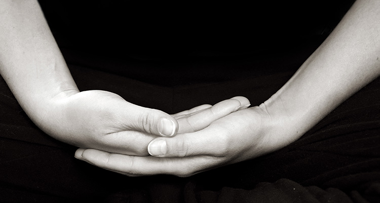 image of hands in meditation posture, contemplating death and impermanence