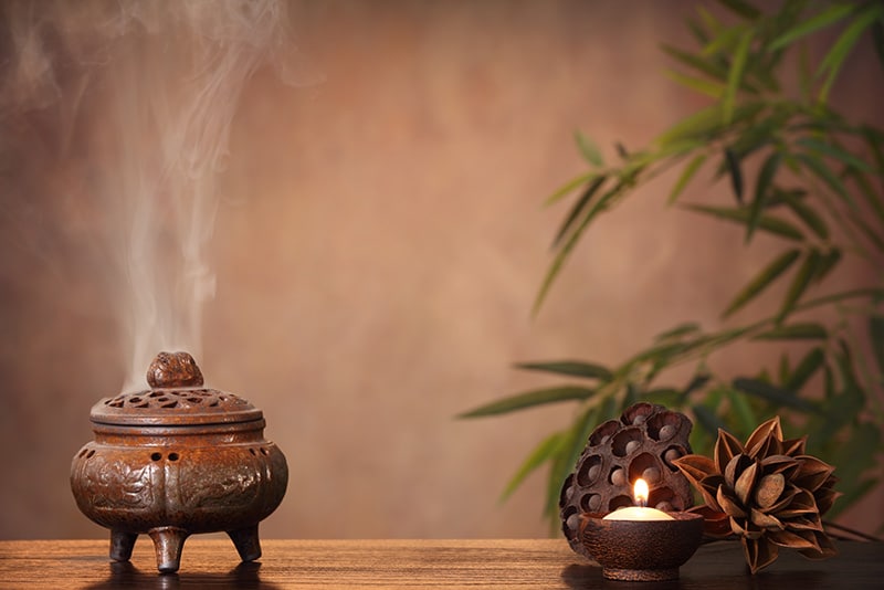 Incense smoke rises beside a candle and bamboo
